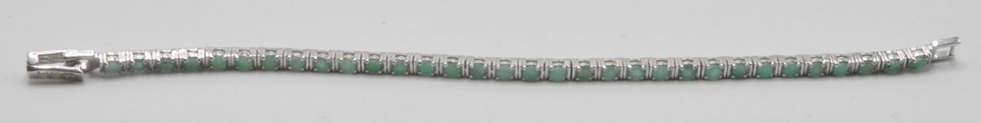 A silver and emerald tennis bracelet being set with round cut green stones. Measures: 7 inch long