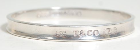 A vintage silver Tiffany bangle bracelet of typical round form with engraved T & Co, the interior