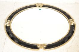 Harrison & Gil - A good large oval gilt and ebonised wall mirror having a large central beveled