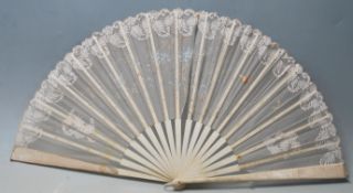 A late 19th / early 20th Century bone and lace hand fan being hand painted with butterflies and