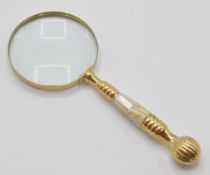 A 20th Century desktop magnifying glass having a white brass banded handle with inlaid mother of