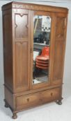 An early 20th Century Edwardian wardrobe having a scrolled top over a single mirrored door between