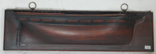A 20th Century Edwardian mahogany half hull of a ship mounted on a wall plaque with two brass