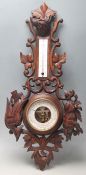 An early 20th Century French carved oak barometer decorated with a wolf, birds and foliate sprays.