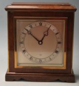 An mid century 1960s Oak mantle clock having a pediment stepped top over a large brass and brushed