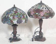 A matched pair of 20th century Tiffany style table lamps, each with shaped columns on circular