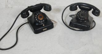 A pair of early 20th century Bakelite telephones in black. Each with ring dials with white numbers