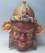 A 20th Century Chinese Tibetan carved wooden wall mounting mask in the form of a demon / mythical