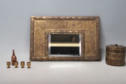 A 20th Century Arts and Crafts style mirror having a brass hammered frame with central bevelled
