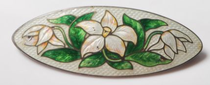 An early 20th Century silver cloisonne enamelled brooch of oval form being decorated with white