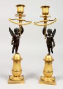 A SUPERB PAIR OF FRENCH EMPIRE BRONZE AND ORMOLU CANDLESTICKS as a pair of winged cupids holding