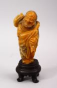 A GOOD QUALITY NATURAL COLOUR CHINESE CARVED SOAPSTONE FIGURE OF ROHAN, stood holding a staff over