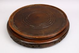 A HUGE 19TH CENTURY CHINESE CARVED HARDWOOD STAND, of cylindrical form with carved apron, housing