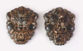 TWO TIBETAN CARVED HARDSTONE PENDANTS OF MYTHICAL MASKS, 8cm high.