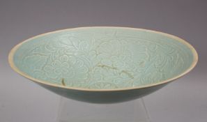 A CHINESE SONG STYLE CELADON POTTERY CARVED BOWL, the bowl carved with floral decoration, the base