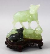 A GOOD CHINESE CARVED JADE / HARDSTONE FIGURE OF A COW AND CALF, stood on a fitted hardwood base,