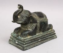 AN EARLY INDIAN OR SOUTH EAST ASIAN BRONZE FIGURE OF AN ELEPHANT, in a recumbent position, 15cm high