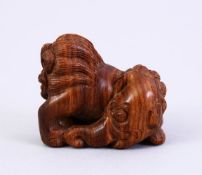 A JAPANESE MEIJI PERIOD STYLE CARVED WOODEN NETSUKE OF A LION ELEPHANT, the lion dog with an