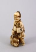 A SMALL JAPANESE MEIJI PERIOD CARVED IVORY NETSUKE - the figure carved holding tied sacks of