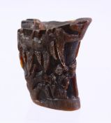 A CHINESE CARVED HORN LIBATION CUP, carved with figures in landscapes, 6cm.