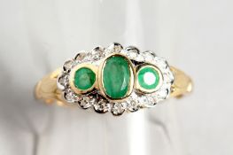 A 9CT GOLD THREE STONE EMERALD AND DIAMOND RING.