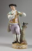 A MEISSEN PORCELAIN FIGURE OF A YOUNG MAN standing beside a tree stump with a bird. Cross swords