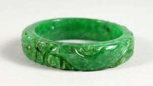 A CHINESE CARVED APPLE GREEN JADE BANGLE. 2.75ins diameter.