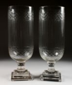 A PAIR OF GLASS STORM LANTERNS with crosshatch and line engraved decoration. 16ins high.