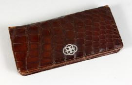 A LADIES CROCODILE LEATHER PURSE, wit silver mount. 8ins long.