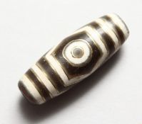 A GOLD INLAID TIBETAN ZHI BEAD. 1.5ins long.