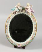 A GOOD 19TH CENTURY MEISSEN OVAL MIRROR with cupid holding a garland. Bevelled mirror 9ins x 7ins.