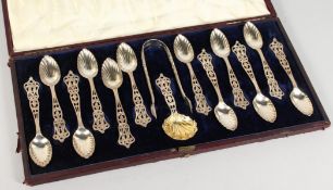 A SUPERB SET OF TWELVE VICTORIAN PIERCED SILVER TEASPOONS, TONGS AND CADDY SPOON in a case. London