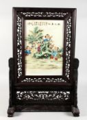A CHINESE PORCELAIN TABLE SCREEN, in a carved hardwood frame. 26.5ins high x 18ins wide.