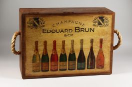 A NOVELTY WOODEN STORAGE BOX the hinged lid decorated with wine bottles. 22ins wide.