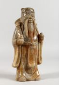 A CHINESE CARVED GREY JADEITE FIGURE OF A STANDING MAN HOLDING A RUI SCEPTRE. 8.5ins high.