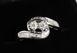 A 9CT GOLD DIAMOND AND BAGUETTE DIAMOND CROSSOVER RING.