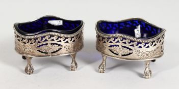 A GOOD PAIR OF GEORGE III PIERCED OVAL SALTS with sapphire blue liners on claw feet. London 1786.