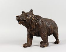 A GOOD BLACK FOREST POTTERY STANDING BEAR. 13ins long.