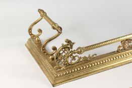 AN ORNATE BRASS FENDER. 59in long x 14.5ins deep.