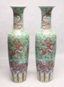 AN IMPRESSIVE PAIR OF CHINESE PORCELAIN FLOOR STANDING VASES, green ground, painted with dragons.