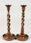 A PAIR OF CIRCULAR WOODEN BARLEY TWIST CANDLESTICKS. 12ins high.