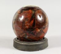 A GLASS BALL containing fifteen million years old petrified rosewood. 4ins diameter.