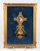 A GILDED METAL AND PORCELAIN HOLY WATER FONT with Madonna and Child. 7.5ins long, 3.5ins wide, on