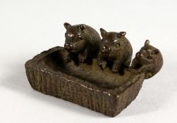 A JAPANESE BRONZE MODEL OF THREE PIGS AT A TROUGH. 2ins long.