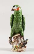 A CONTINENTAL PORCELAIN PARROT standing on a tree stump. Blue cross with letter T. 11ins high.
