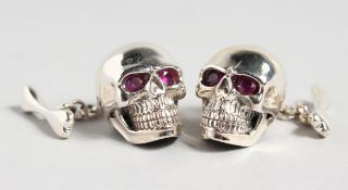 A PAIR OF SILVER SKULL CUFFLINKS with ruby eyes.