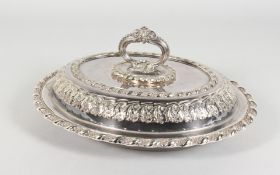 A GOOD PLATED OVAL ENTREE DISH, COVER AND HANDLE, with embossed decoration. 12ins wide.