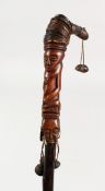 A NATIVE STICK carved with heads and shells. 37ins long.