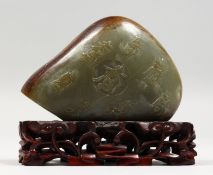 A SMALL JADE SCHOLAR'S ROCK WITH CARVED DECORATION, on a pierced wood stand. 4ins high.