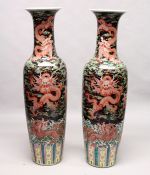 AN IMPRESSIVE PAIR OF CHINESE PORCELAIN FLOOR STANDING VASES, black ground, painted with dragons.